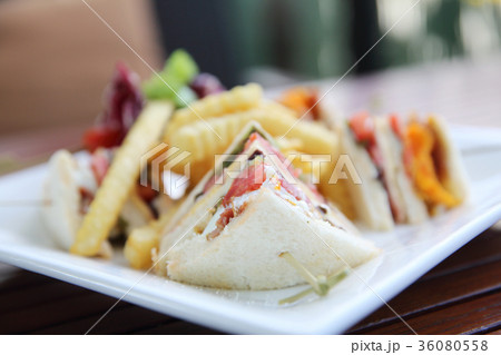 Club sandwich with chicken breast , bacon , tomato , cucumber and fried potatoes 36080558