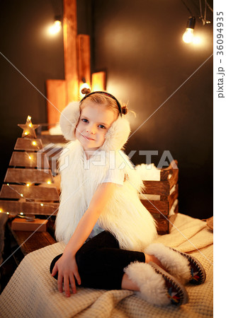 Cute little girl in fur earmuffs sitting near 36094935