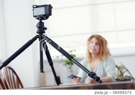 Photo of woman blogger at atable with florarium. 36099373