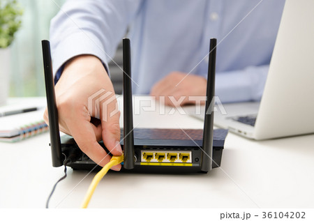 Man plugs Ethernet cable into router 36104202