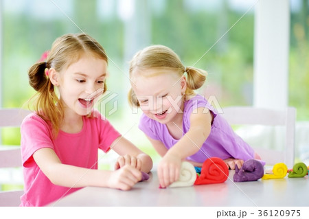 Two cute little sisters having fun together with colorful modeling clay at a daycare 36120975