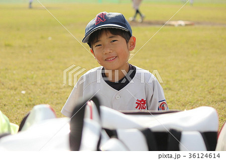 試合中 出番なく暇そうに笑顔を向ける野球少年 幼児 の写真素材