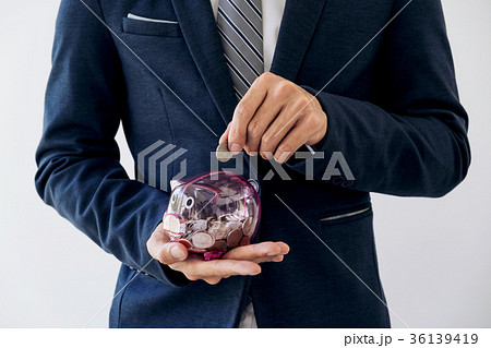 Businessman putting coins into piggy bank, financial and investm 36139419