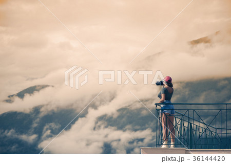 A female photographer with a camera on the balcony A female photographer with a camera on the balcony 36144420
