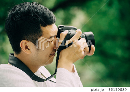 カメラを構える若い男性 新緑の写真素材
