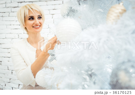Woman decorating white and gold Christmas tree 36170125