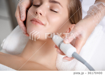 Calm young woman getting cavitation rejuvenation Calm young woman getting cavitation rejuvenation 36170400