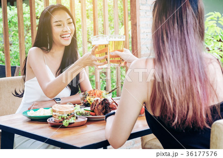 Young asian women drinking beer and clink glasses Young asian women drinking beer and clink glasses 36177576