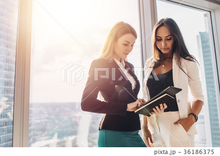 Two female colleagues with tablet computer while Two female colleagues with tablet computer while 36186375