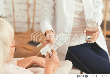 Young nurse consulting aged patient at home Young nurse consulting aged patient at home 36199466