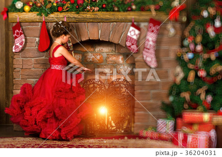 Little winter Princess warms at burning fireplace 36204031