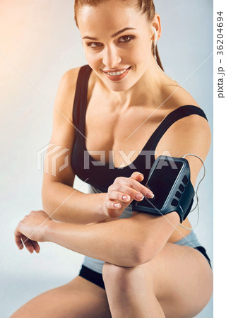 Charming female athlete sitting on floor and using 36204694