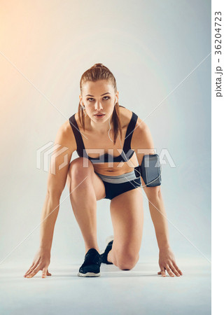 Serious young sportswoman preparing for run Serious young sportswoman preparing for run 36204723