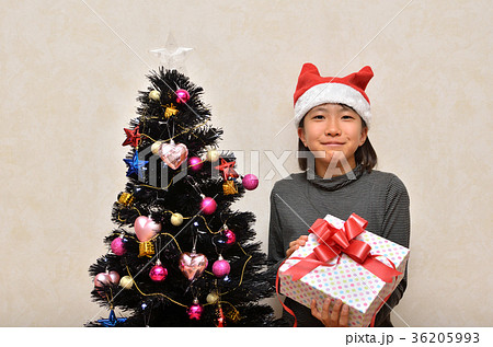 プレゼントを差し出す女の子 クリスマスツリー の写真素材