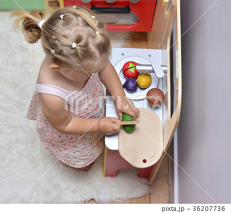 girl cuts wooden vegetables on toy kitchen 36207736
