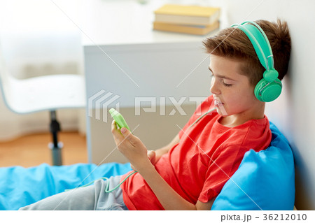 happy boy with smartphone and headphones at home happy boy with smartphone and headphones at home 36212010