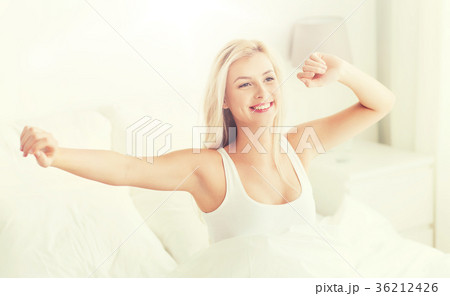 young woman stretching in bed after waking up 36212426