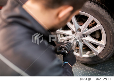 auto mechanic with screwdriver changing car tire 36212911