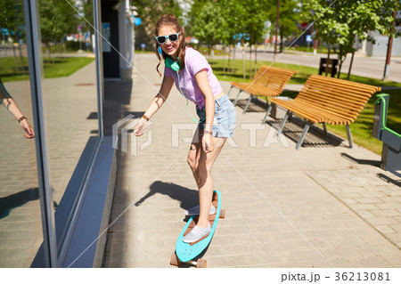 happy teenage girl in shades riding on longboard 36213081