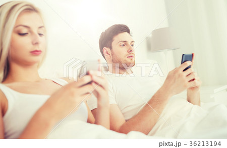 couple with smartphones in bed couple with smartphones in bed 36213194