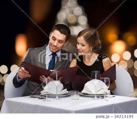 smiling couple with menus at christmas restaurant smiling couple with menus at christmas restaurant 36213195