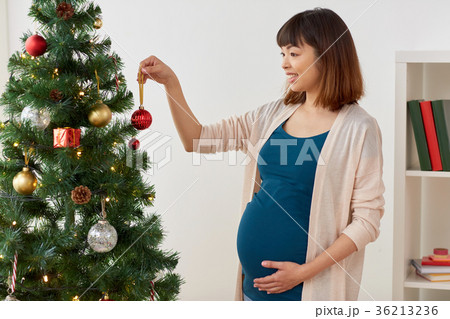 pregnant woman decorating christmas tree at home 36213236