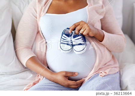 pregnant african woman with baby bootees in bed pregnant african woman with baby bootees in bed 36213664