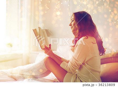 happy young woman reading book in bed at home happy young woman reading book in bed at home 36213809