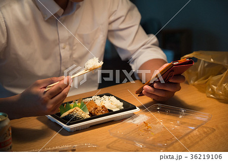 スマホを見ながら弁当を食べる男性 36219106