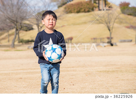 サッカーボールを持つ泣いている男の子の写真素材