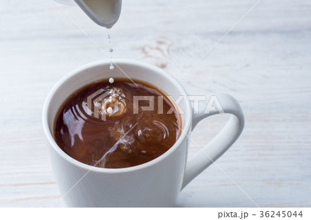 Adding milk to a cup of coffee 36245044