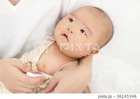 体温計で赤ちゃんの熱を測るの写真素材
