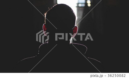 Silhouette of man standing by large window looking Silhouette of man standing by large window looking 36250082
