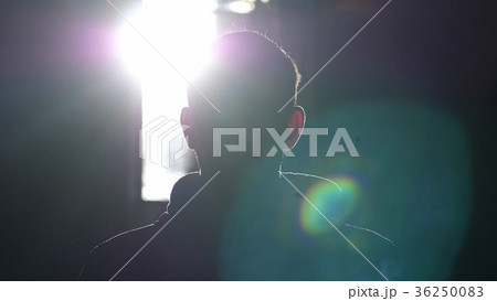 Silhouette of man standing by large window looking 36250083