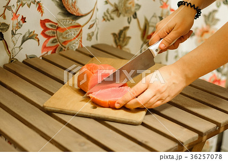 Woman cutting fresh salmon fillet on wooden board 36257078
