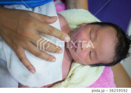 The newborn sleeps in his mother's lap happily  36259592