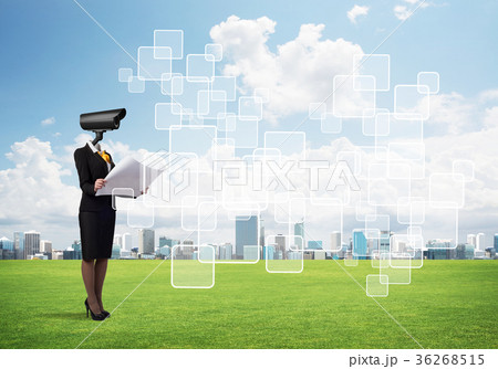 Camera headed woman standing on green grass against modern cityscape Camera headed woman standing on green grass against modern cityscape 36268515