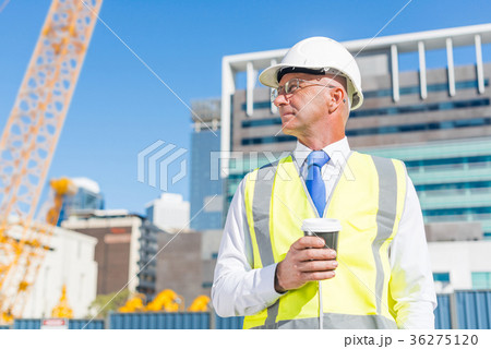 Engineer builder on construction site at sunny day with coffee in hand Engineer builder on construction site at sunny day with coffee in hand 36275120