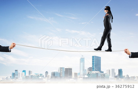 Business concept of risk support and assistance with man balancing on rope Business concept of risk support and assistance with man balancing on rope 36275912