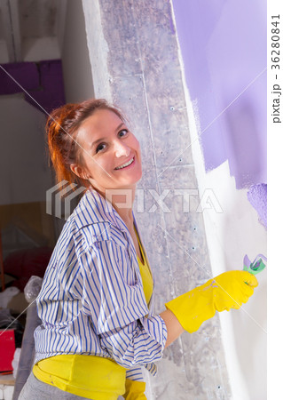 woman paints wall with purple paint roller 36280841