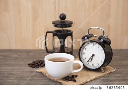 Hot cup of coffee and alarm clock on wood table. 36285903
