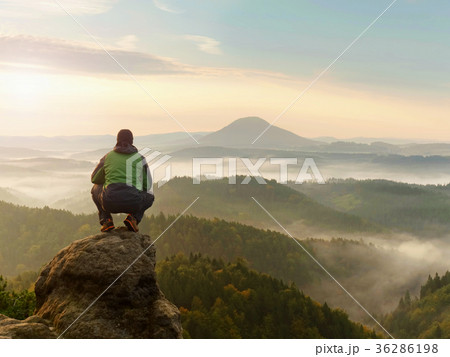 Man on peak within daybreak and watch over mist 36286198