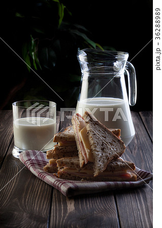 Sandwich and pitcher of milk. Dark tone. Sandwich and pitcher of milk. Dark tone. 36288989