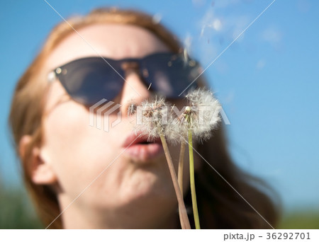 girl in sunglasses blows away dandelion 36292701