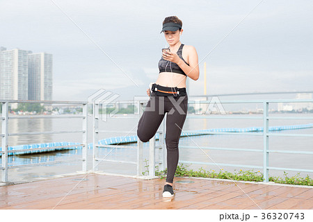 asian woman doing stretching exercises outdoors along city sidew 36320743