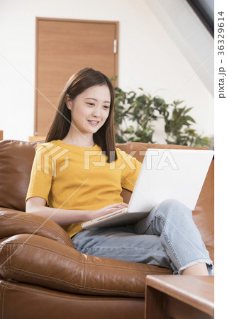 自宅リビングのソファーでパソコンをする若い女性 36329614