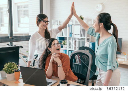 two young business people giving high-five two young business people giving high-five 36352132