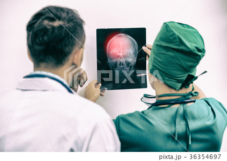 Doctors looking at x-ray film of patient 's head 36354697