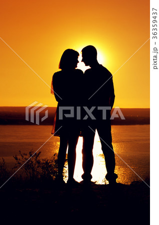 Silhouette of man and woman near sea at sunset Silhouette of man and woman near sea at sunset 36359437
