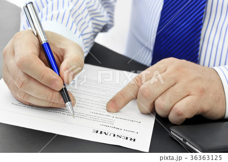 Businessman with pen analyzing resume at desk in t Businessman with pen analyzing resume at desk in t 36363125
